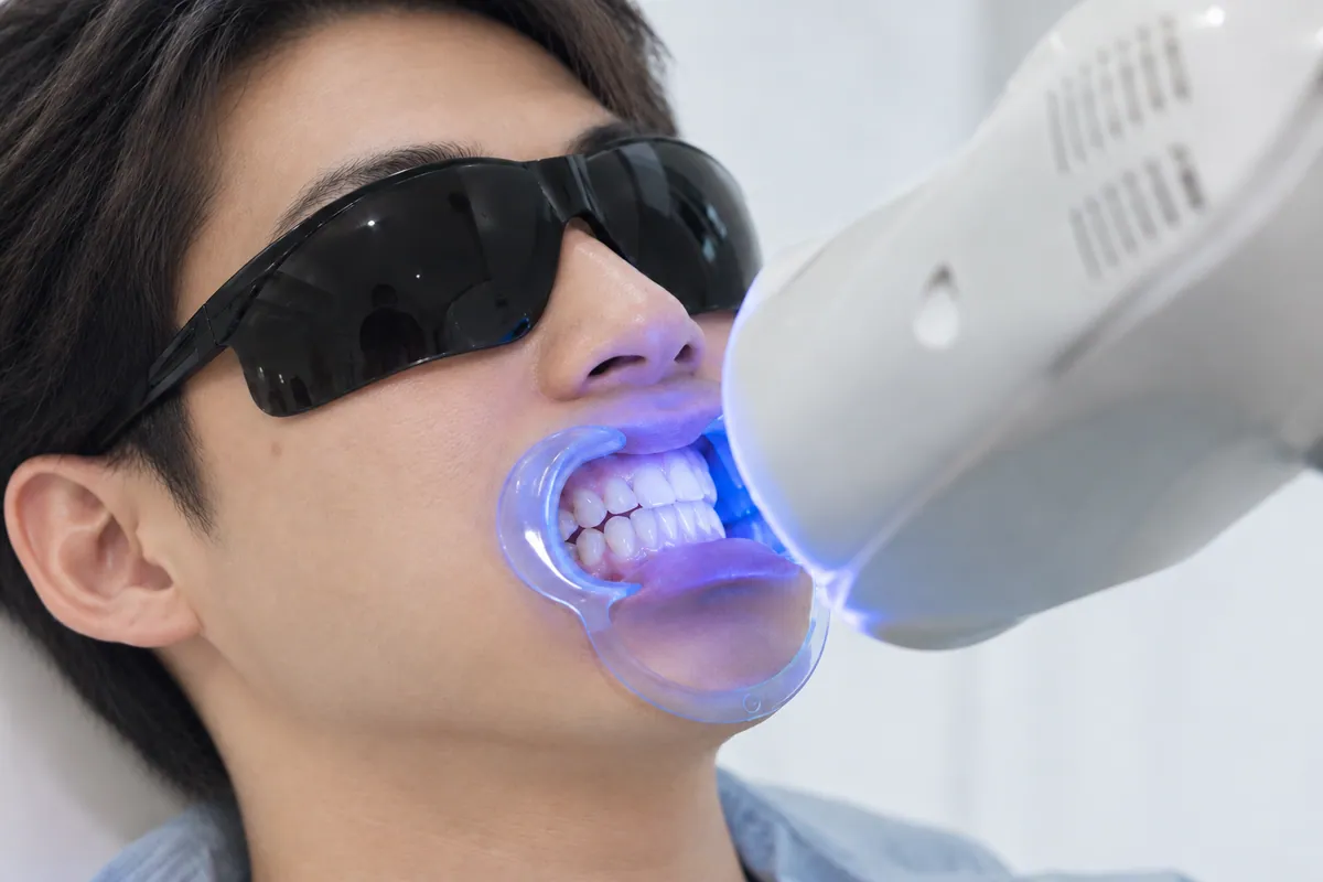 保護メガネを着けた男性の口元にLEDライトを当てる利用イメージ